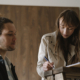A woman looking at her notes with another man