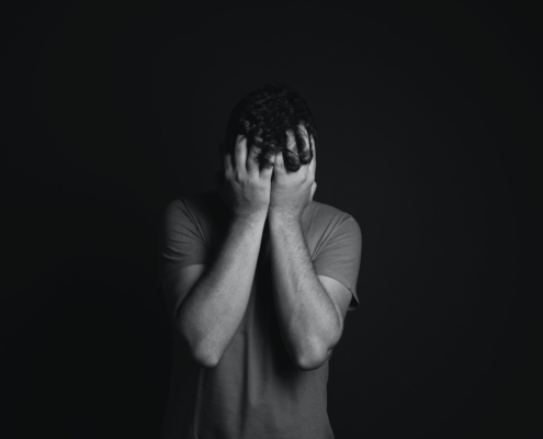 A man with covering his face with his hands